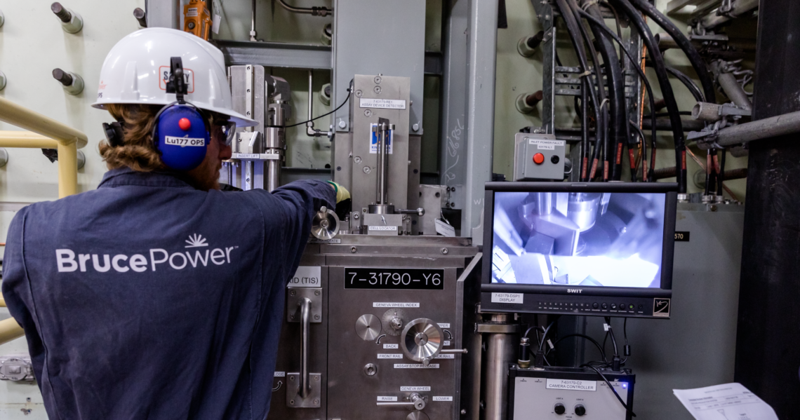 Male operator in blue overalls operating the Isotope Production System