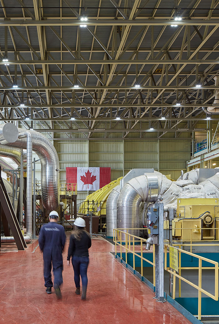 A photograph of two Bruce Power workers walking through the generating station with their protective gear on.