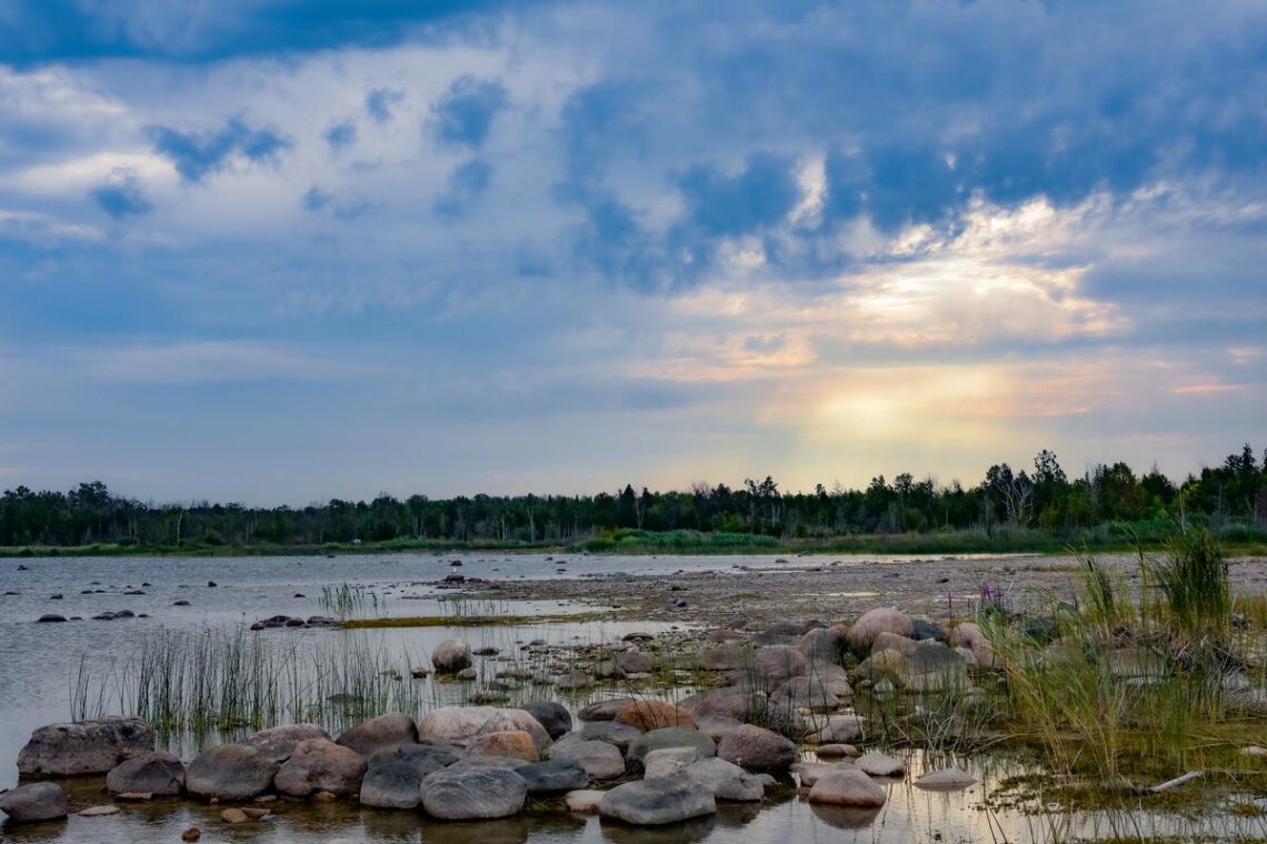 Photograph of a Baie Du Dore Beach with the sun glowing behind some clouds