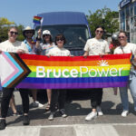 people hold a Bruce Power Pride banner at a local event