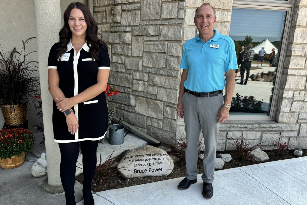 Huron Hospice donation photo with Bruce Power's Calista Powell and Willy Van Klooster in front of building with commemorative stone.