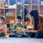 a teacher sits and shows something to students in a classroom