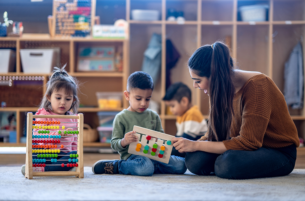 a teacher sits and shows something to students in a classroom