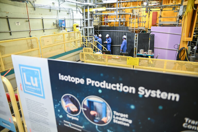 Bruce Power isotope production system. Workers pictured in station near IPS and sign.