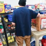 A person in a community foodbank stocking shelves.