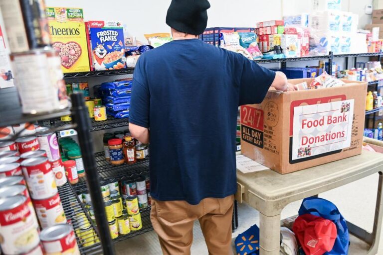 A person in a community foodbank stocking shelves.