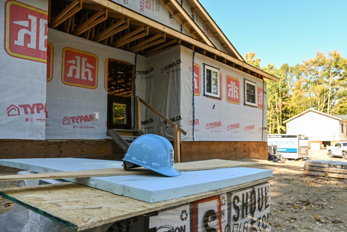 Home construction site showing partially finished home, hard hat. Saugeen First Nation.