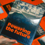 Hand holding Bruce Power's Annual Report Powering the Future with pages displayed in background.